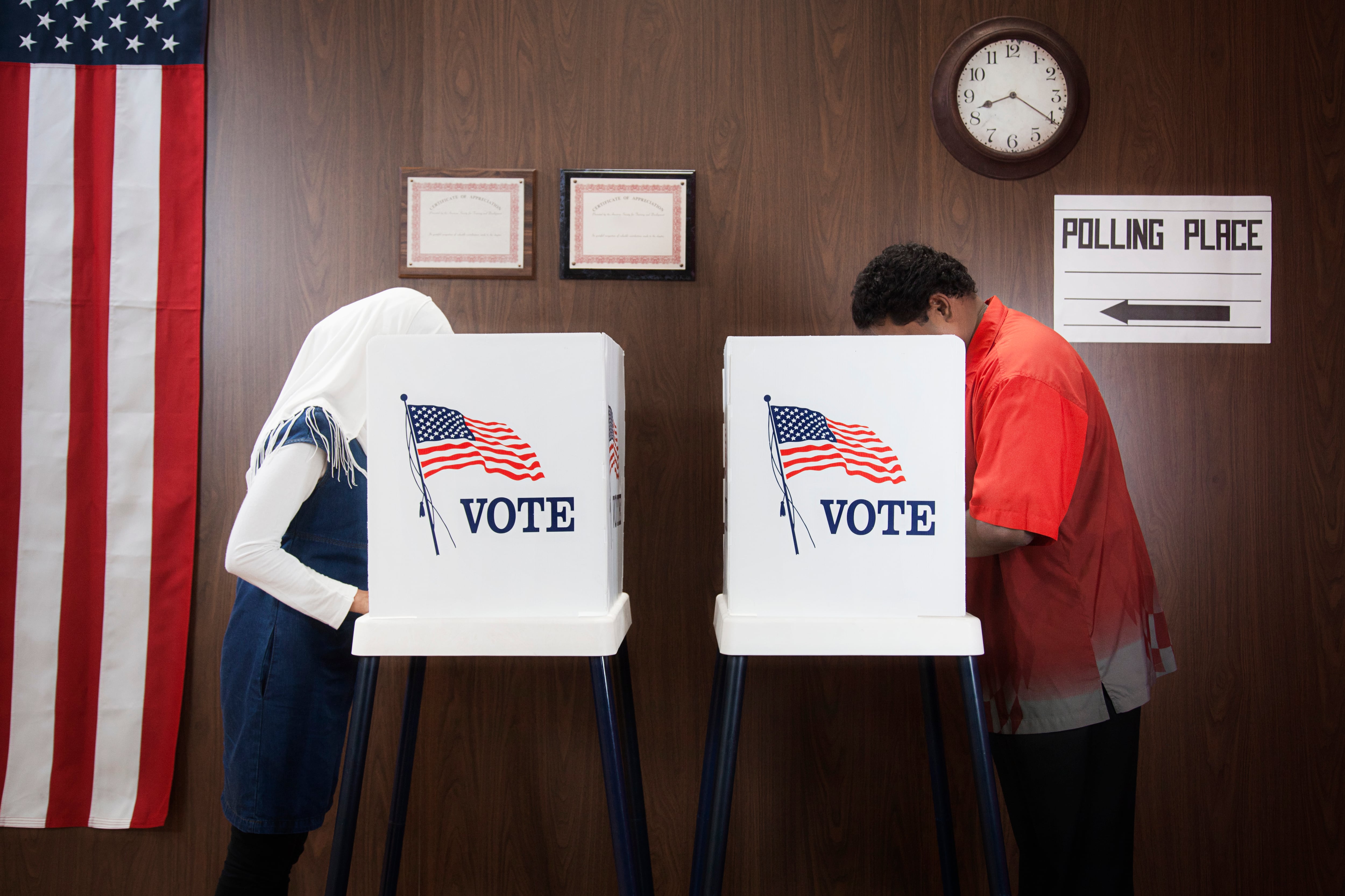 Two people stand at voting machines.
