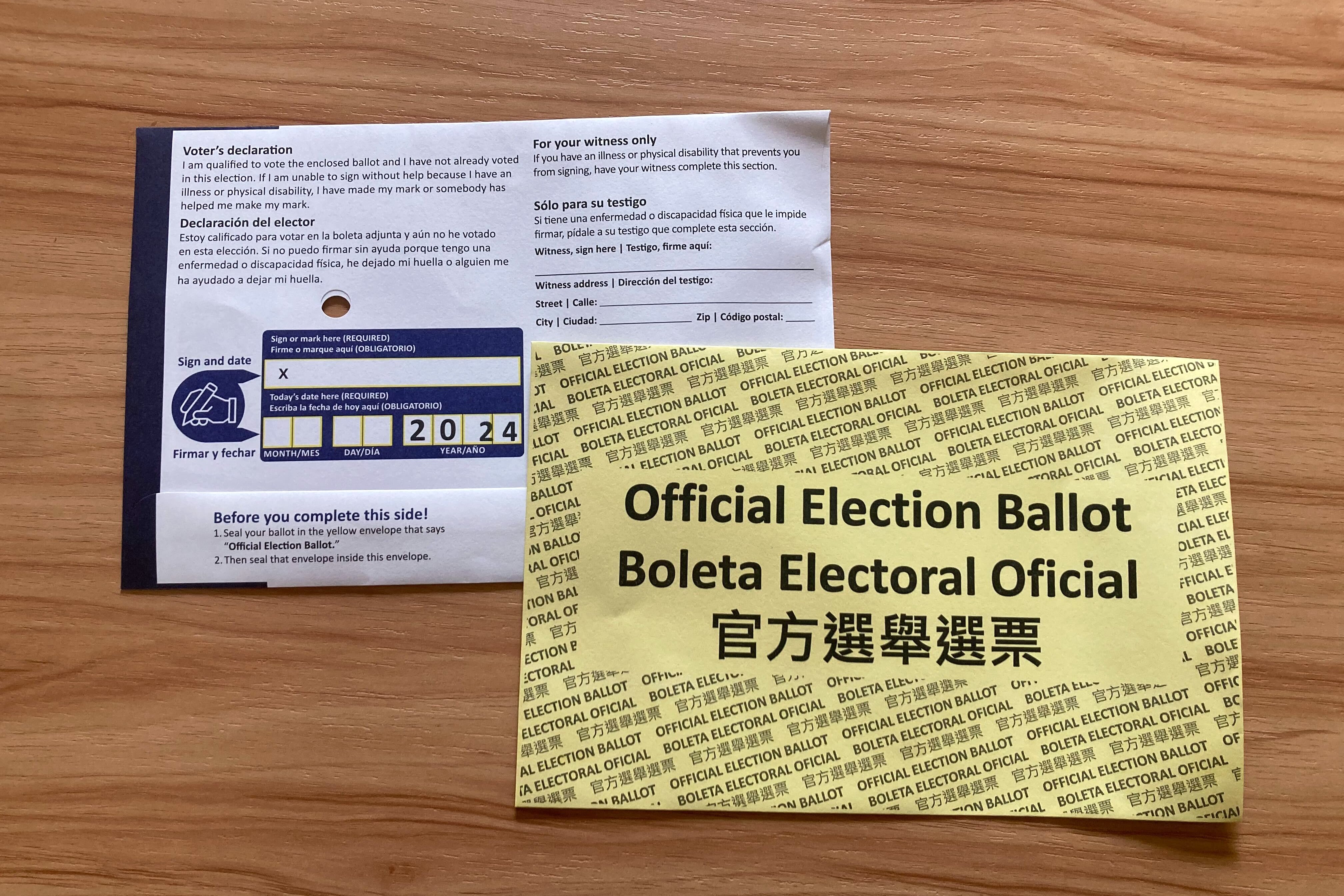 One white and one yellow election ballots sit on top of a wooden table.