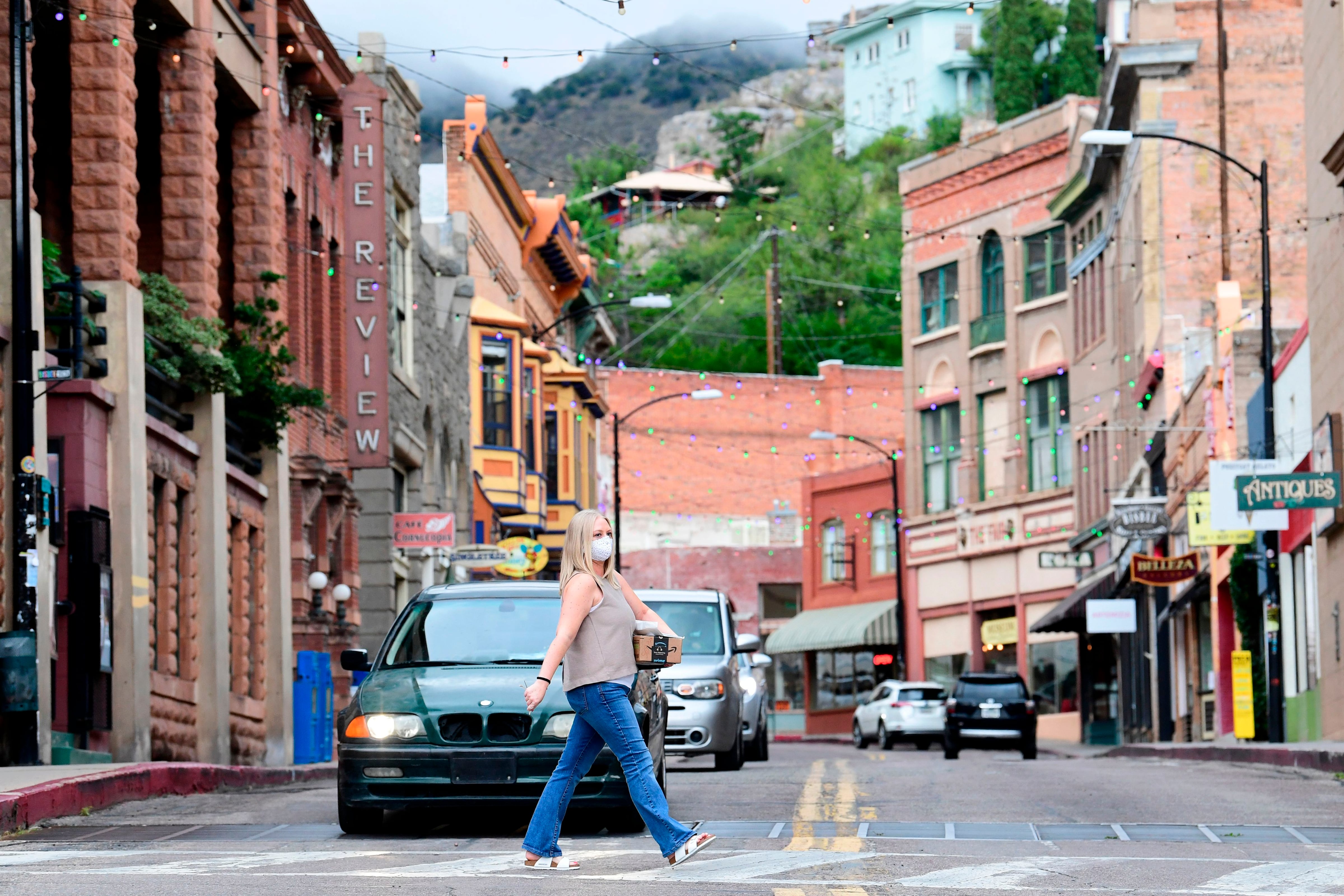 A pedestrian in a face mask crosses a street.