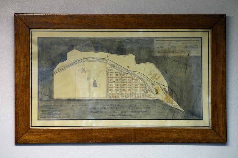 An old map sits in a dark wooden frame hanging on a wall.