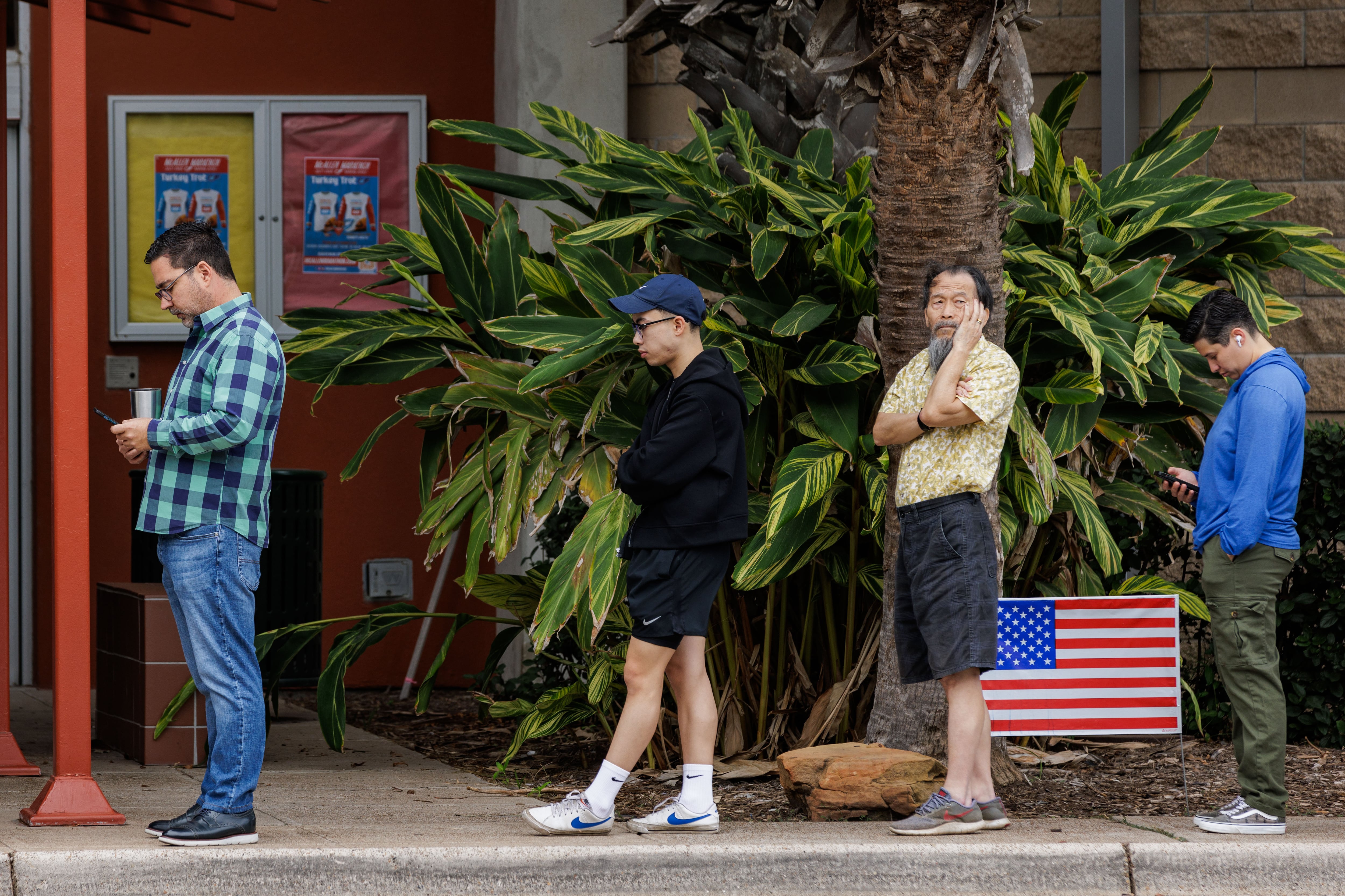 Four people stand in line in front of a small American flag.
