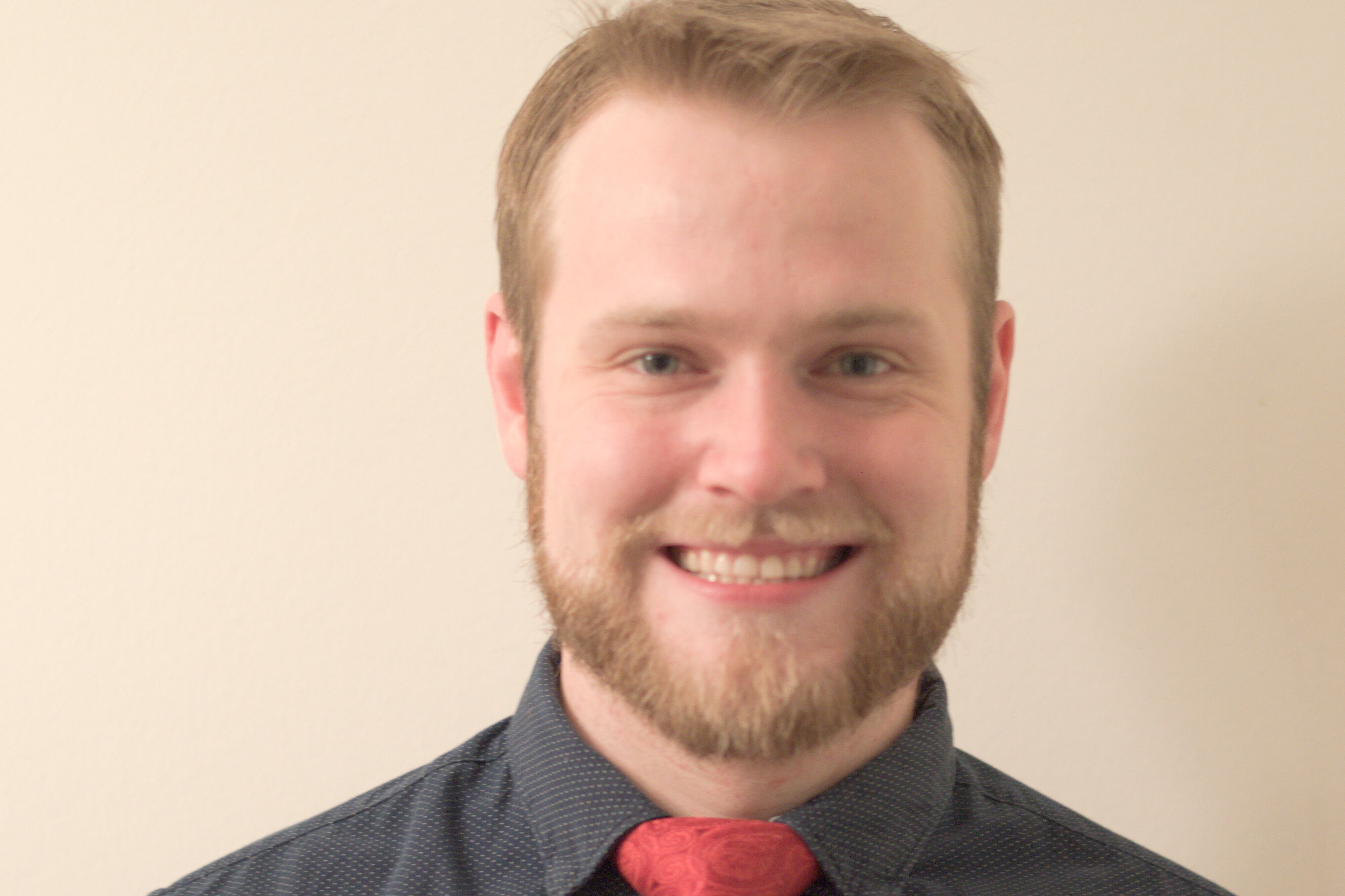 Portrait of a young man in a dark shirt and red tie