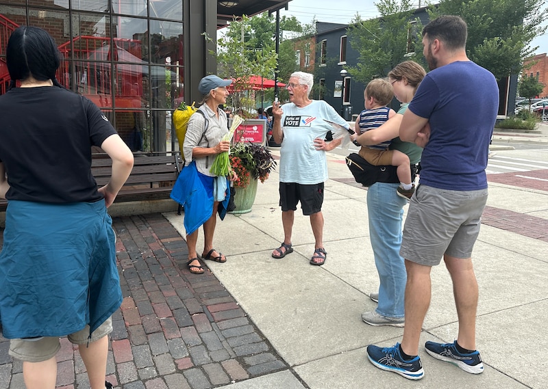 A group of people stands on a sidewalk.