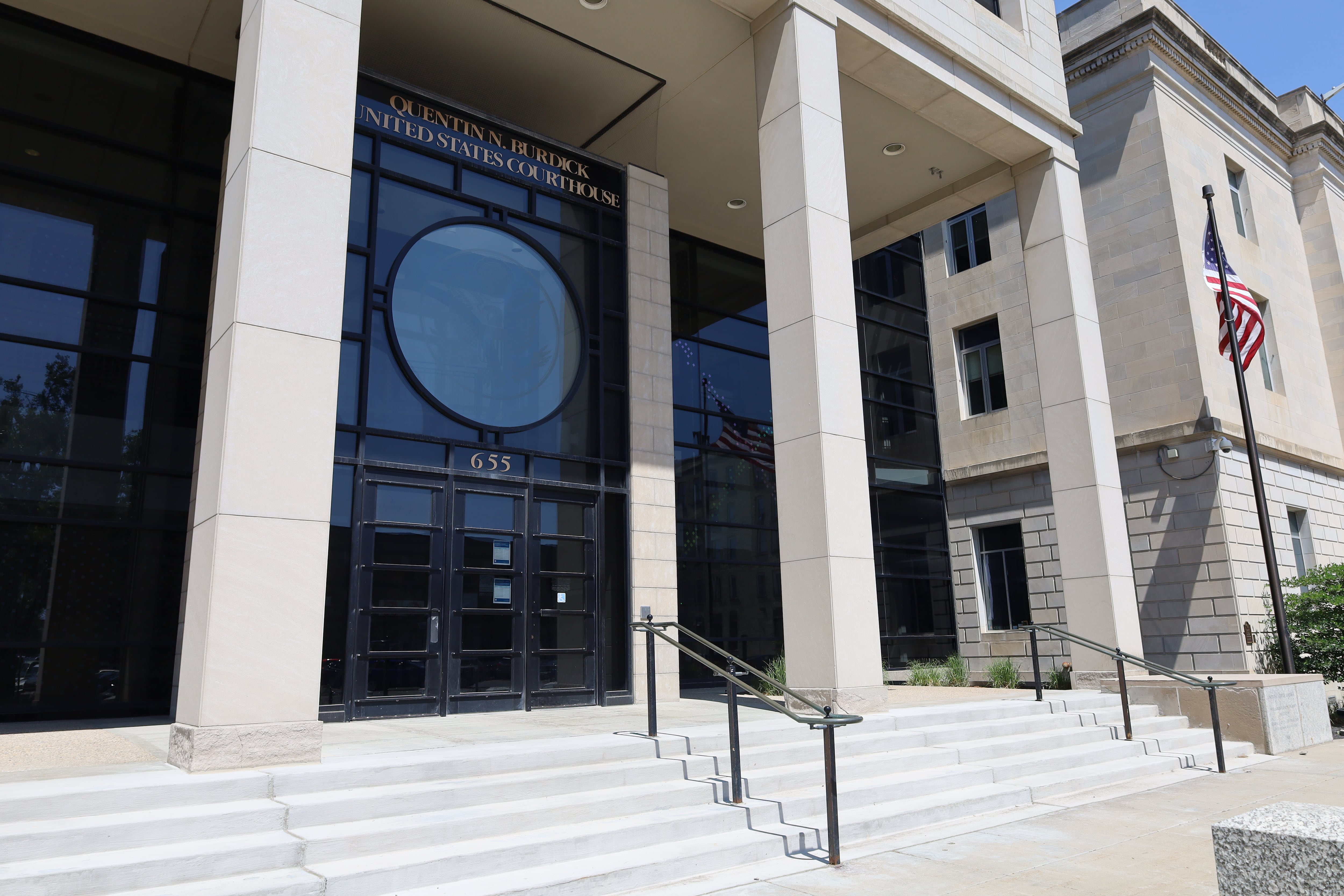 Steps lead up to the front of a building with columns and large glass windows.