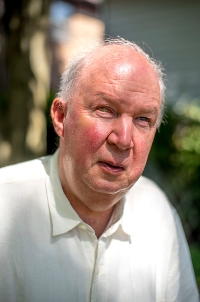 A man wearing a white shirt poses for a photograph.