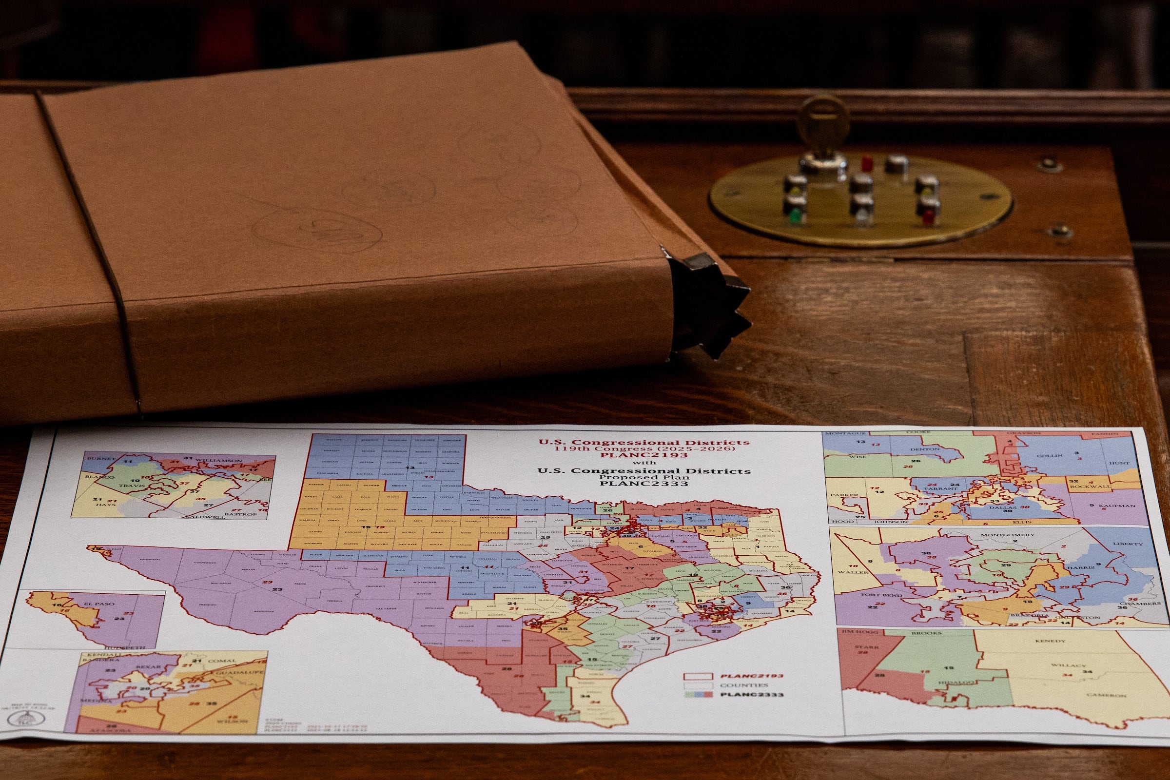 An up-close photograph of a colorful map of Texas sitting on a wooden desk next to a brown folder.