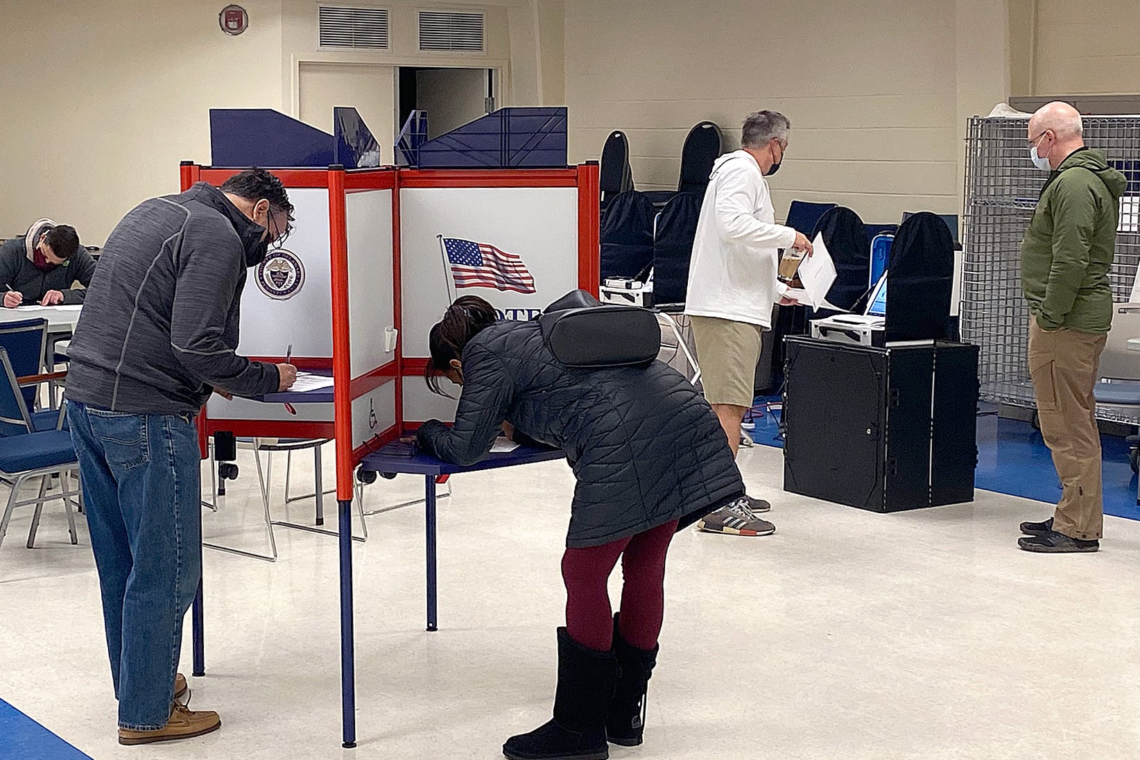 A man and a woman stand at a divided booth, filling out ballots