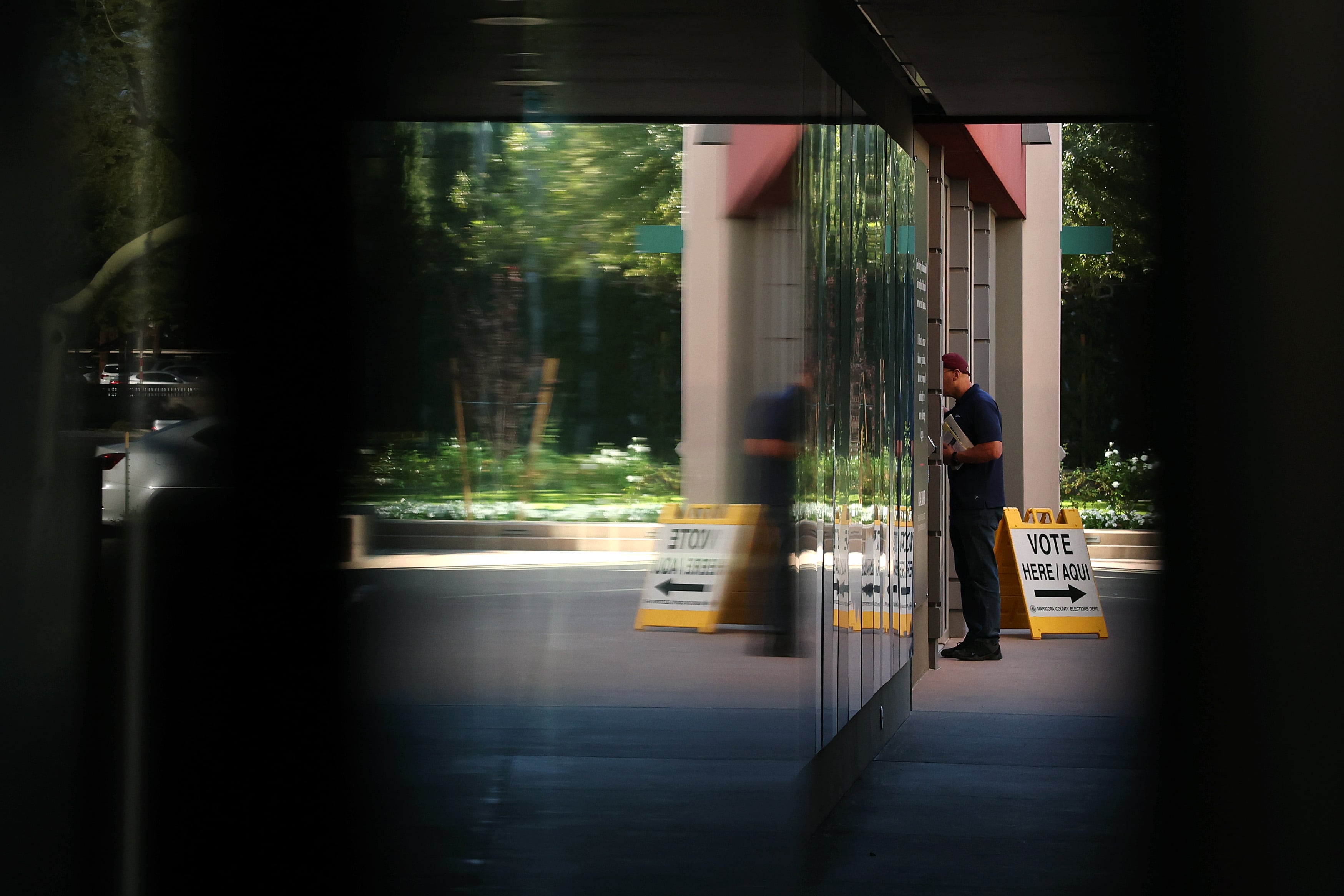 person exits glass door with vote here sign nearby