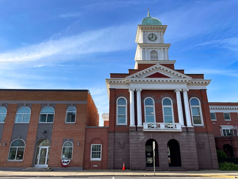 A large colonial style brick building with a blue sky in the background.