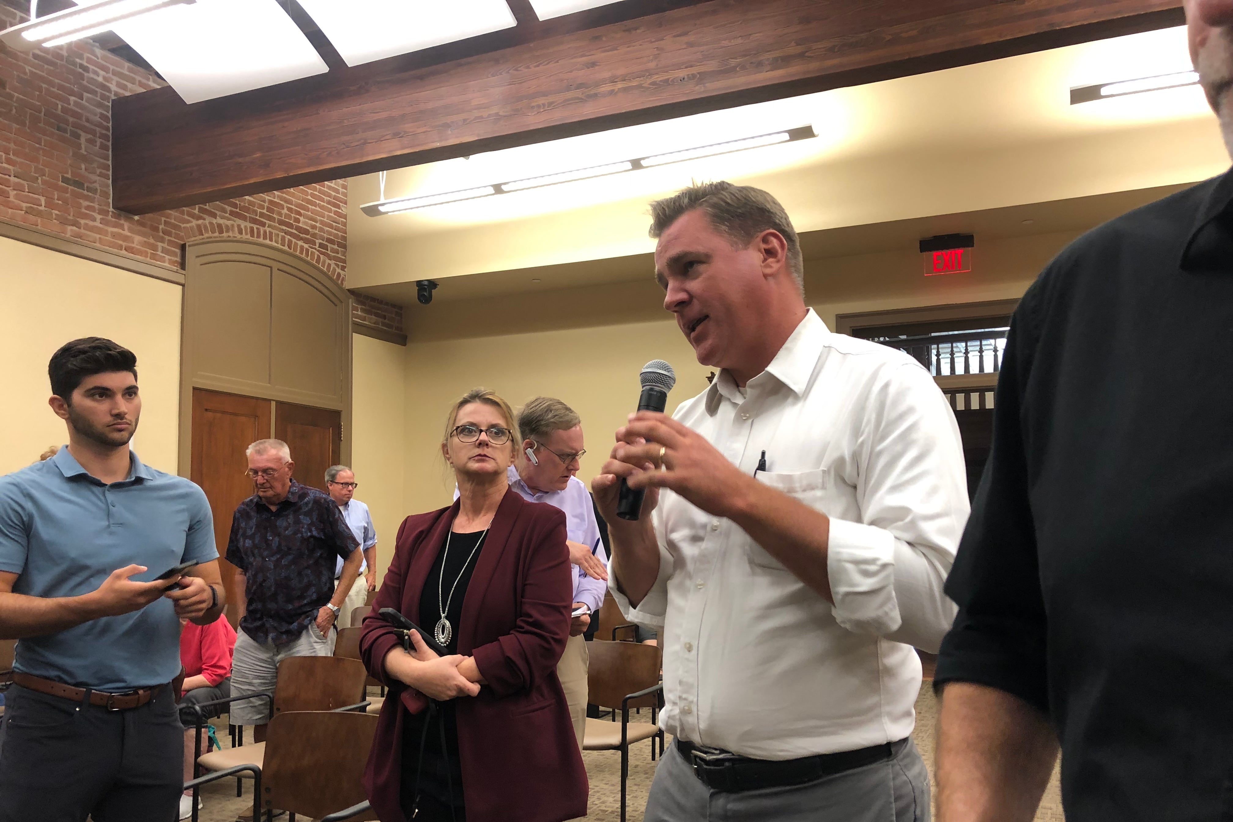 A man speaks into a microphone in a crowded meeting room