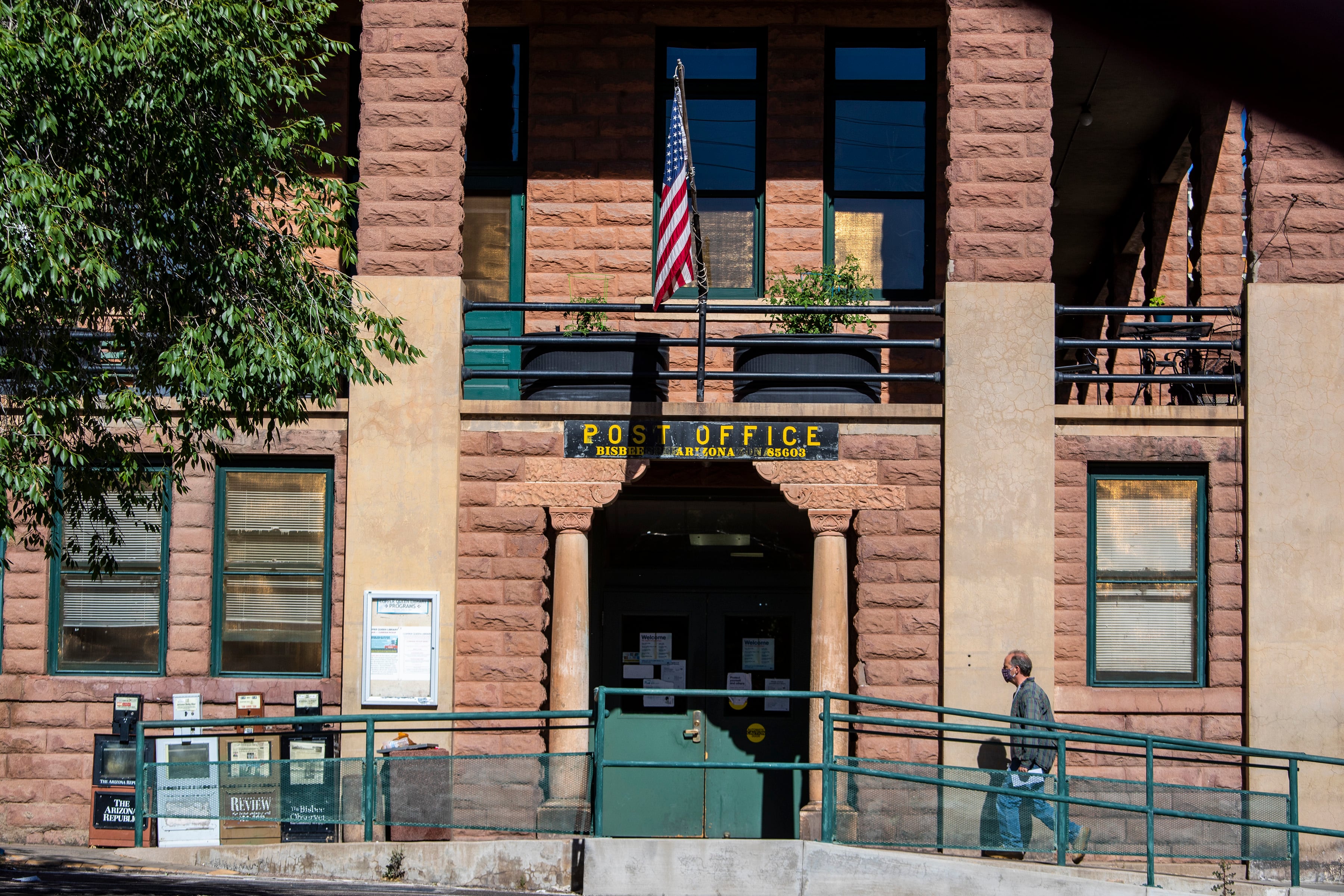 A man walks toward the door of a stone building
