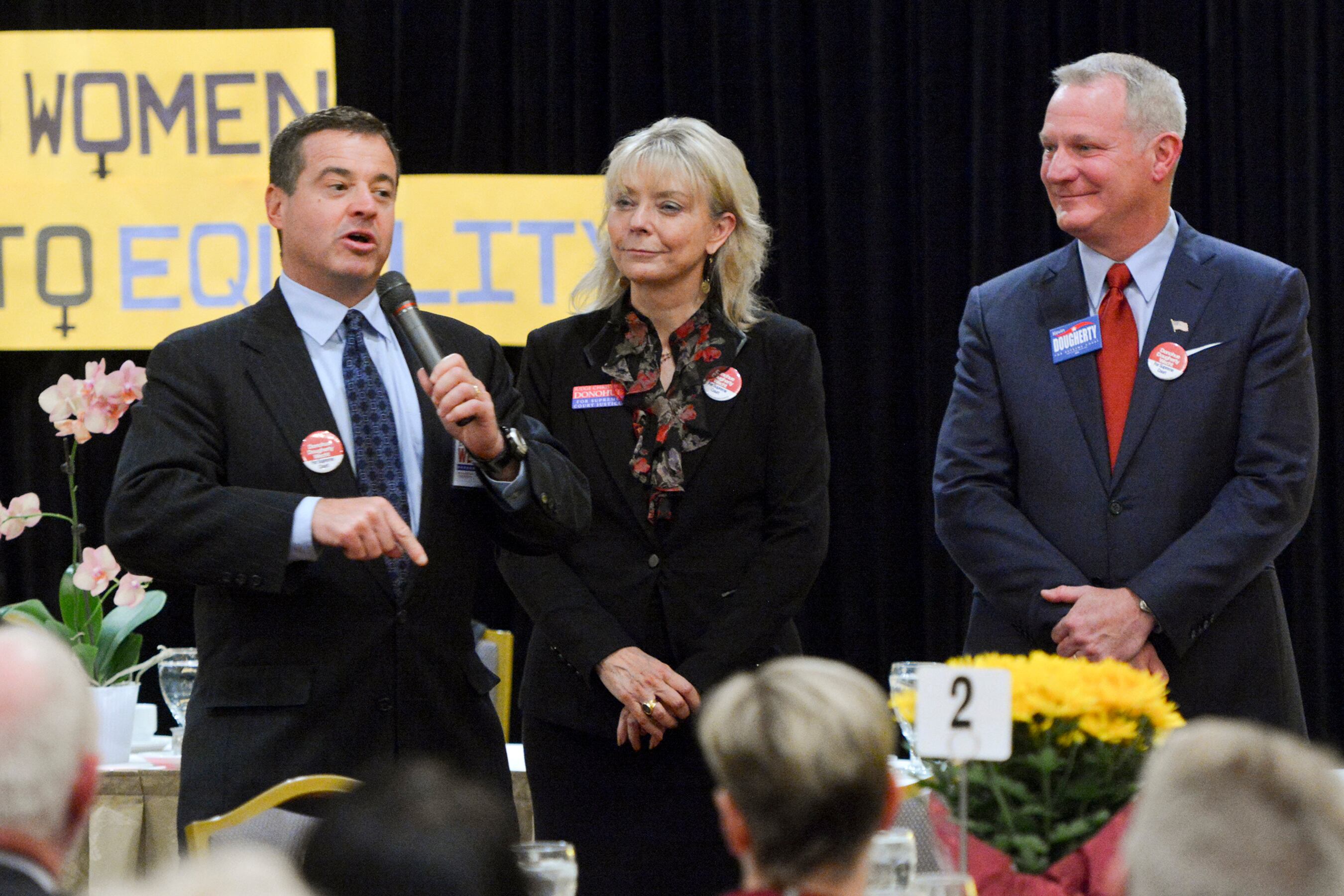 A photograph of three adults standing next to each other in suits.