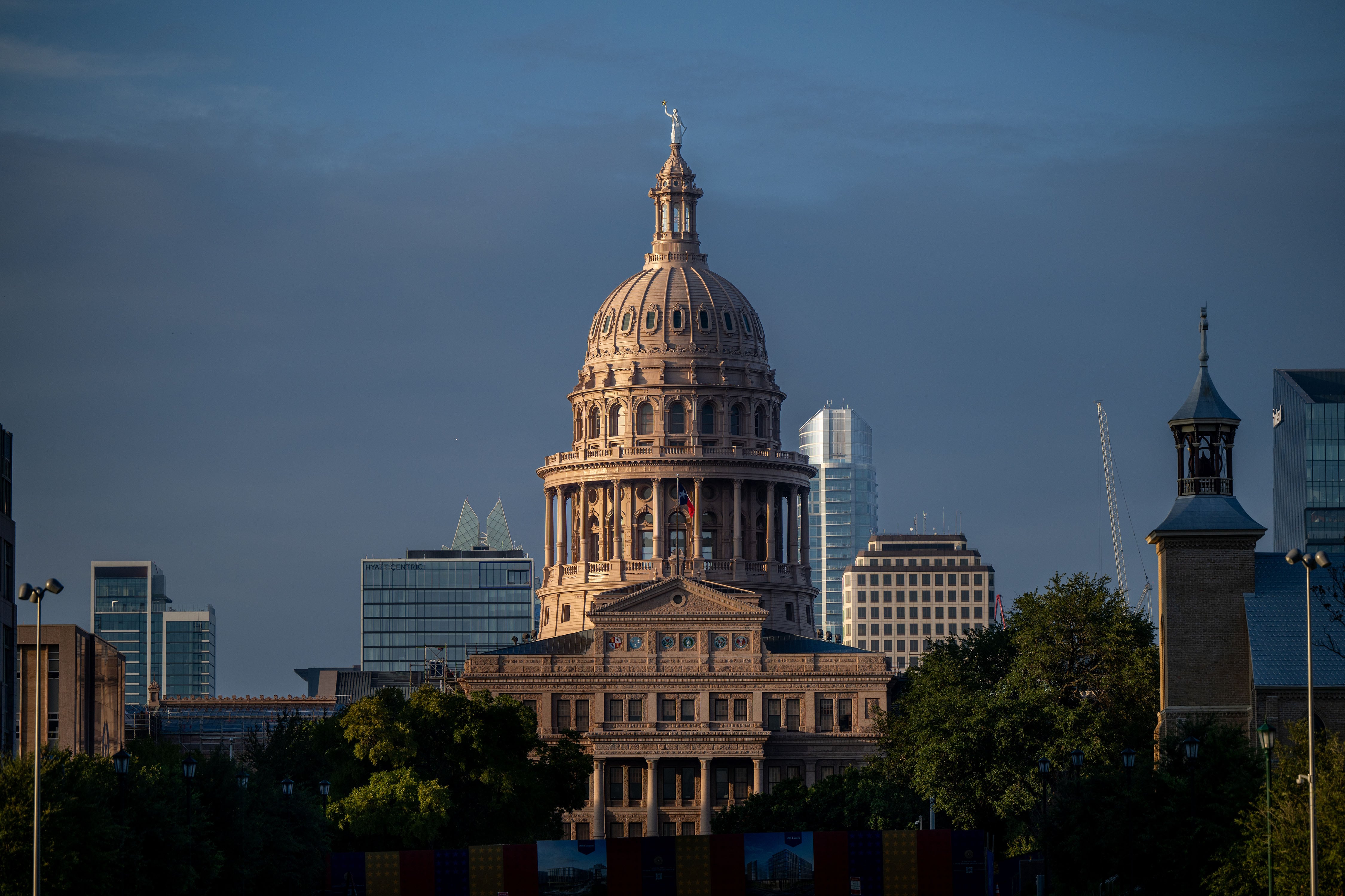 A large stone capitol building with a blue sky and building in the background.