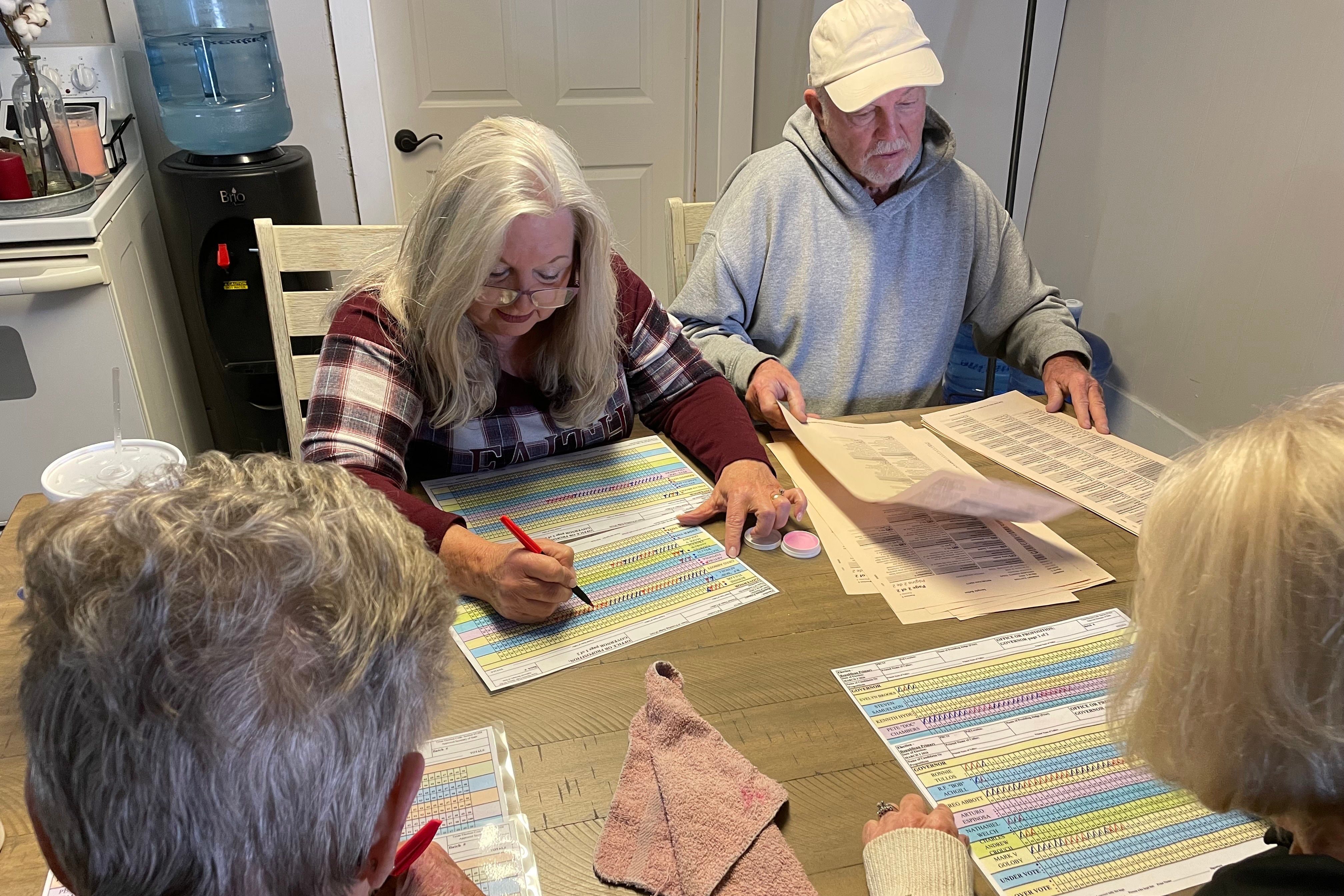A photograph of four white people working on documents all sitting a table.