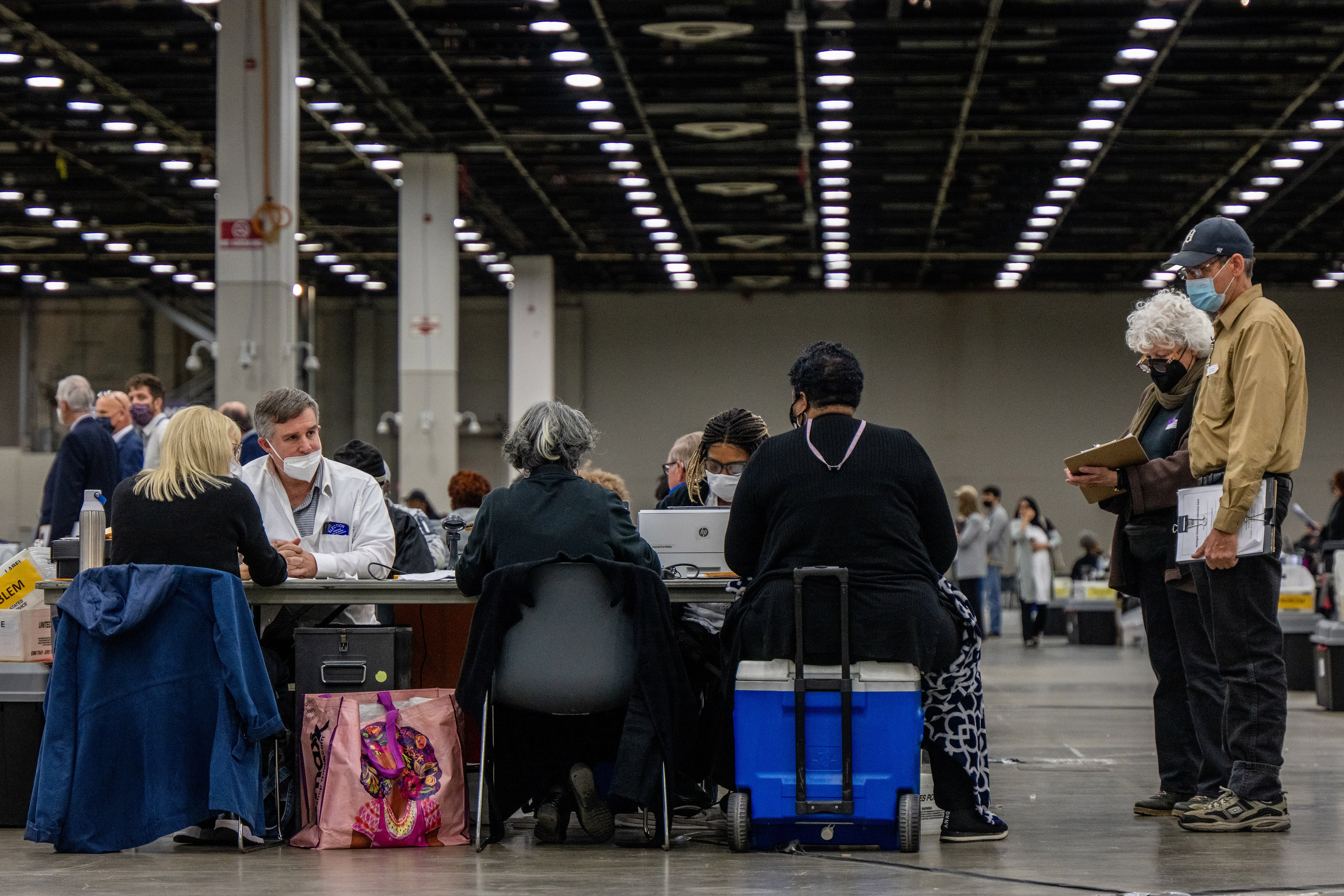 People sit at a table while two people stand to the side.