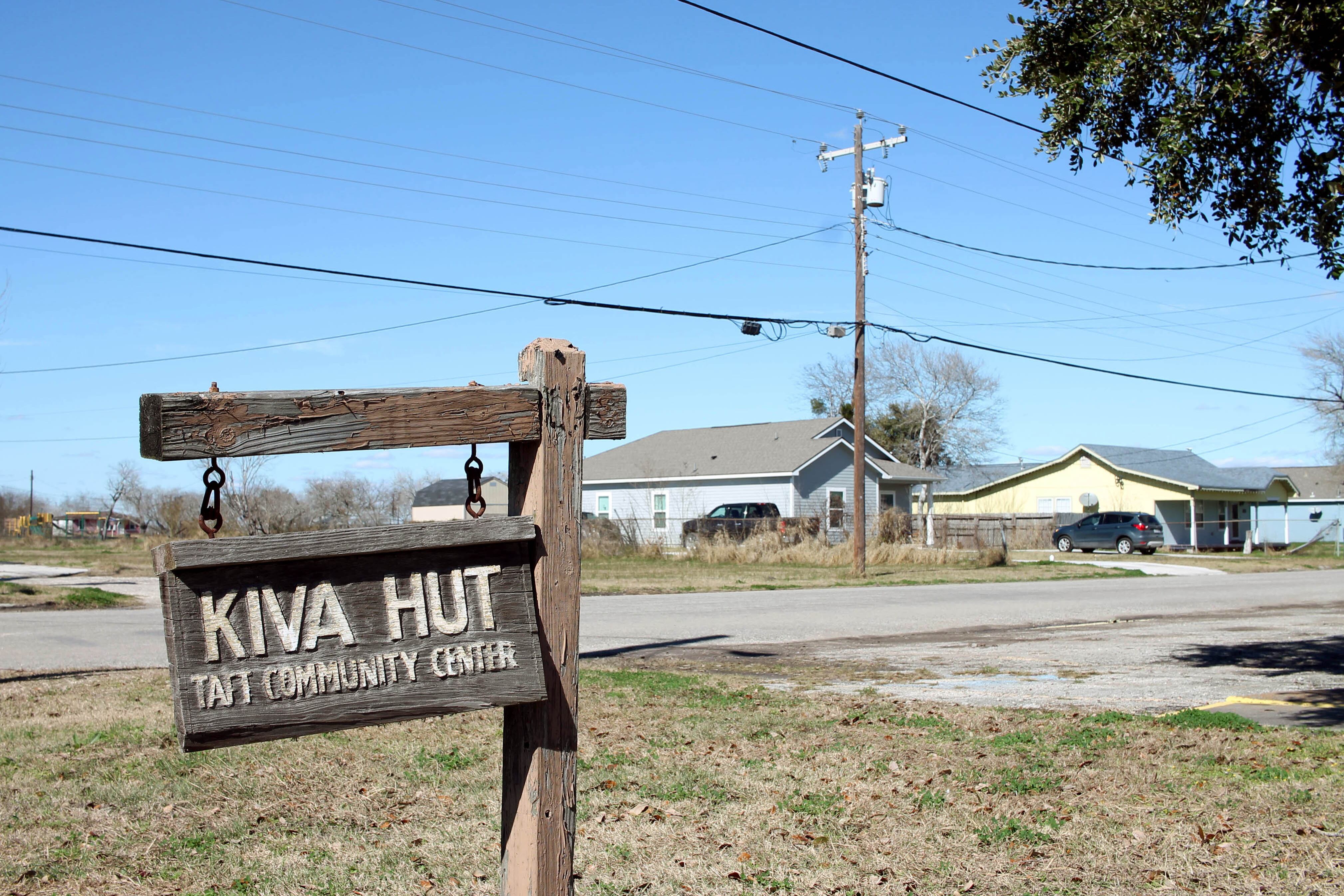 A wooden sign that says "Kiva Hut" and a telephone pole and a house in the background.