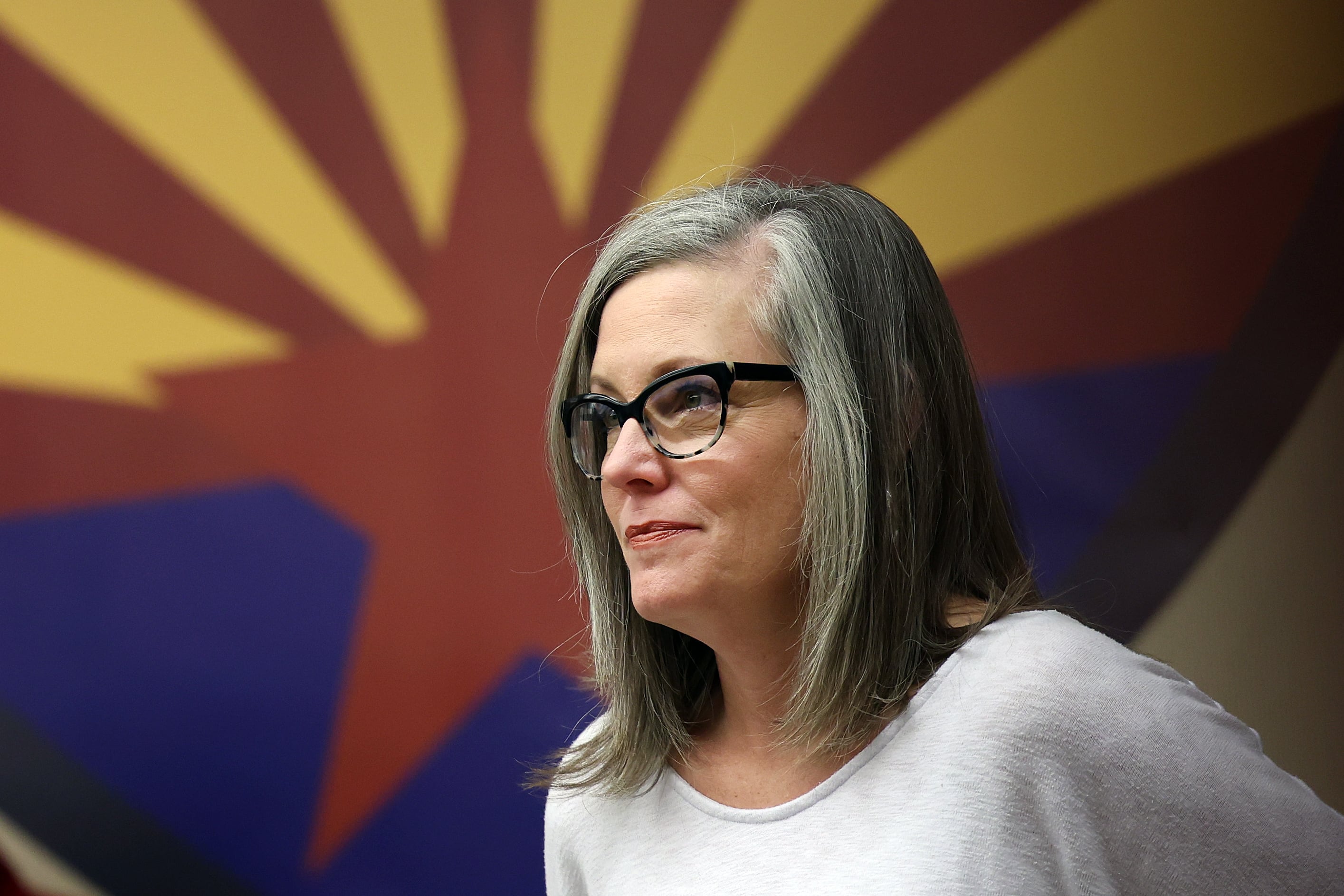 A woman stands in front of Arizona’s orange-and-yellow star-shaped emblem