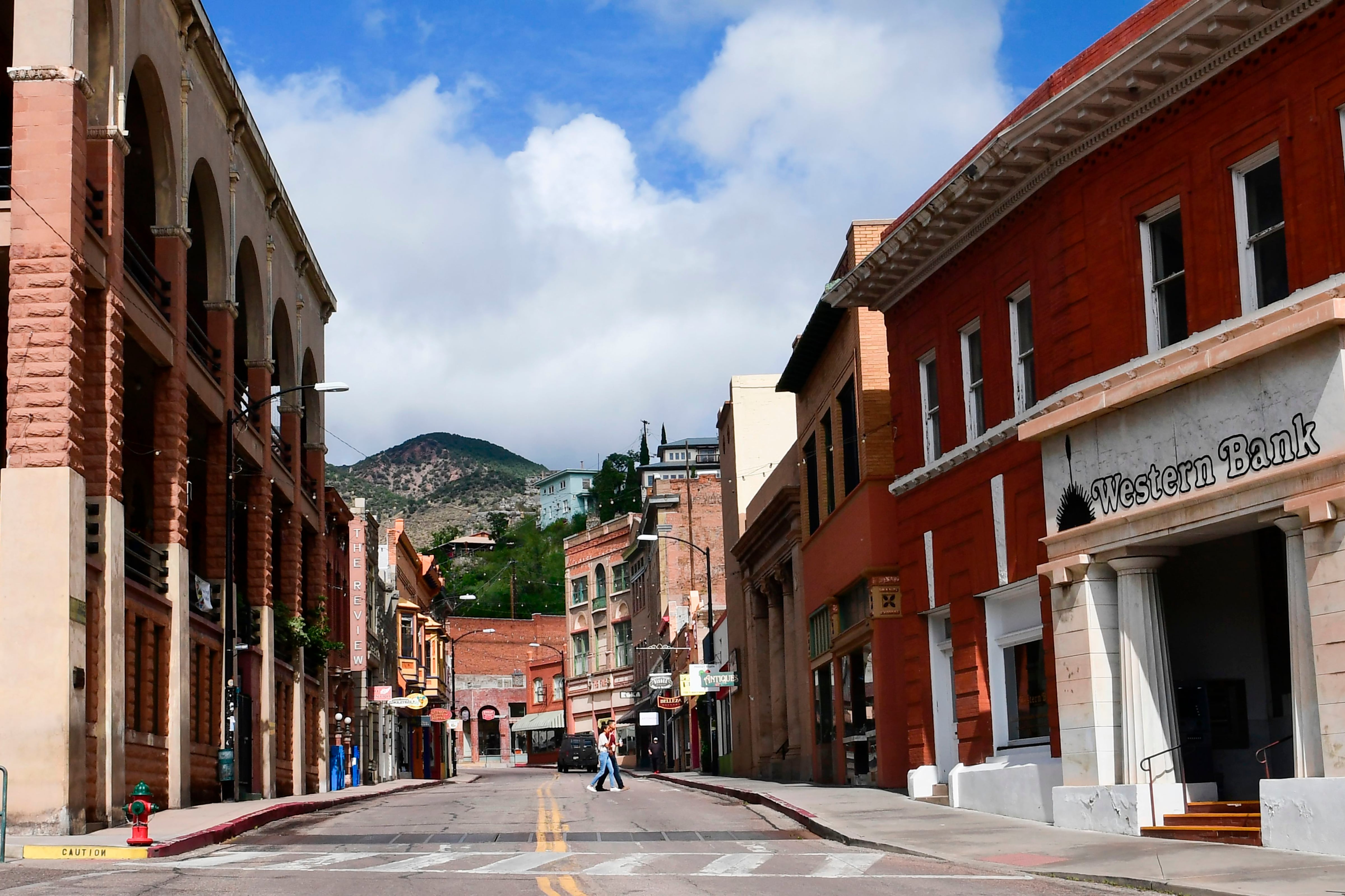 A street lined by brick buildings, one fronted by a sign reading “Western Bank.”