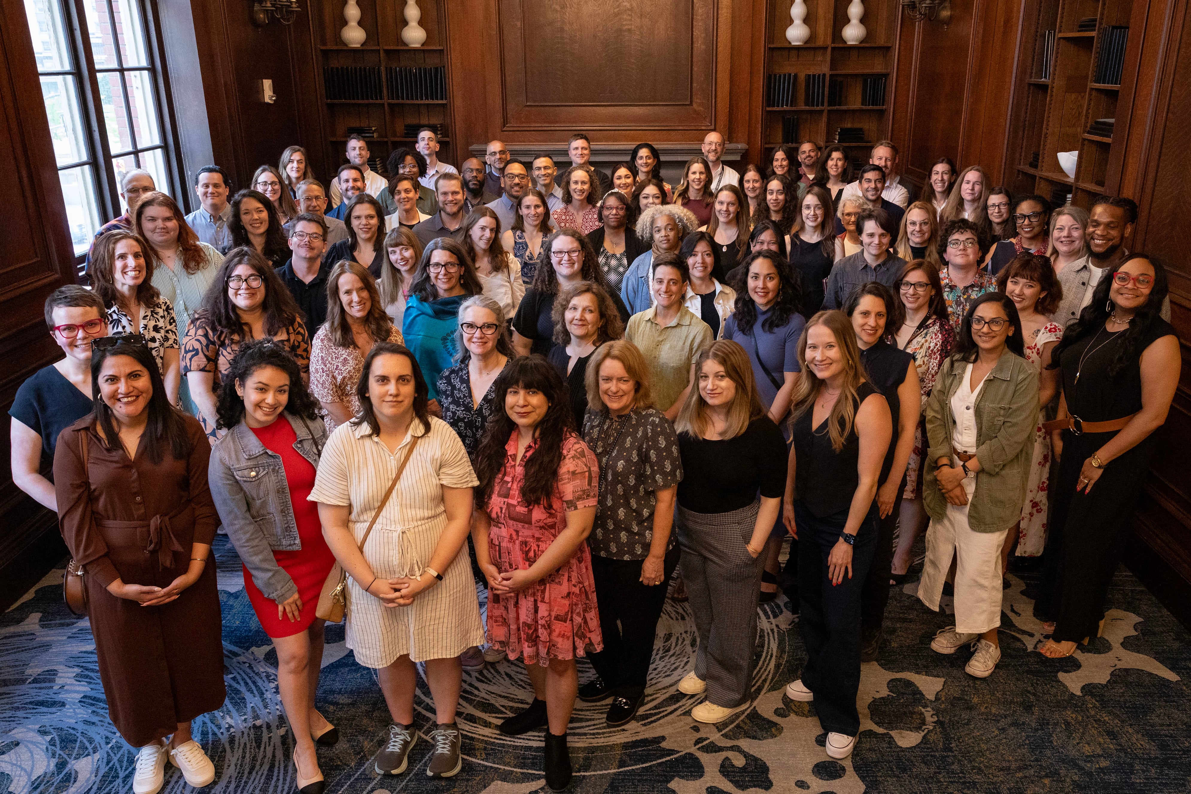 A large group of people stand in a library posing for a photograph.