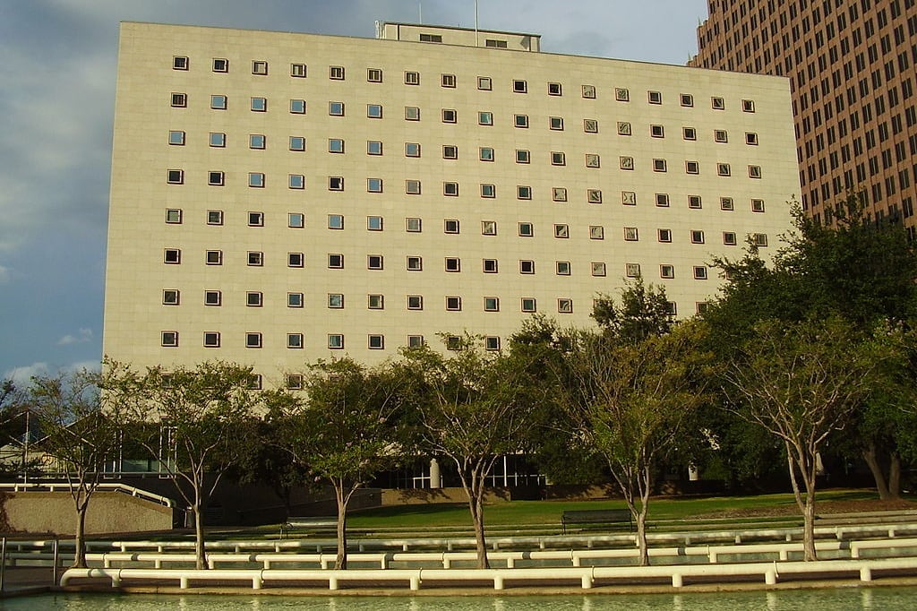 A large, windowed rectangular building surrounded by trees