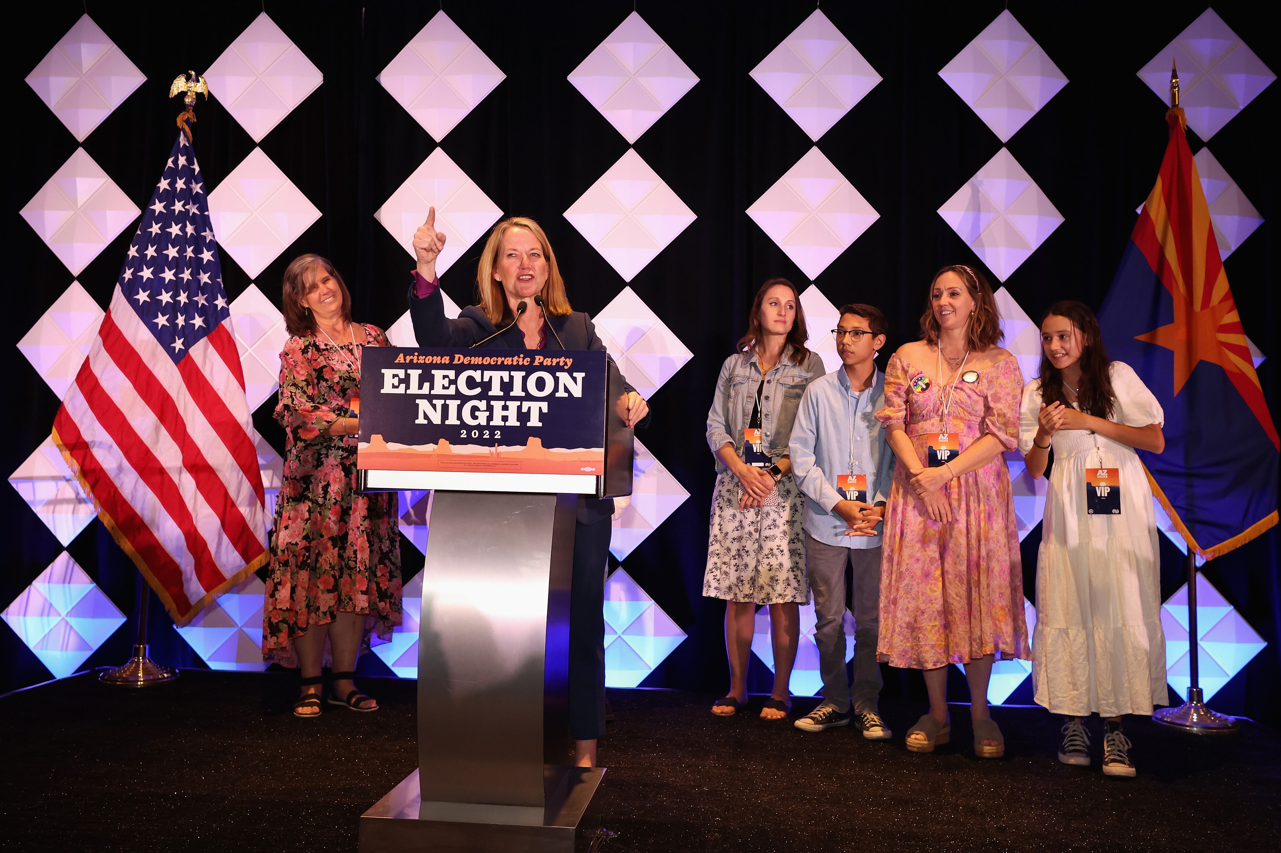 woman on stage behind podium pointing finger