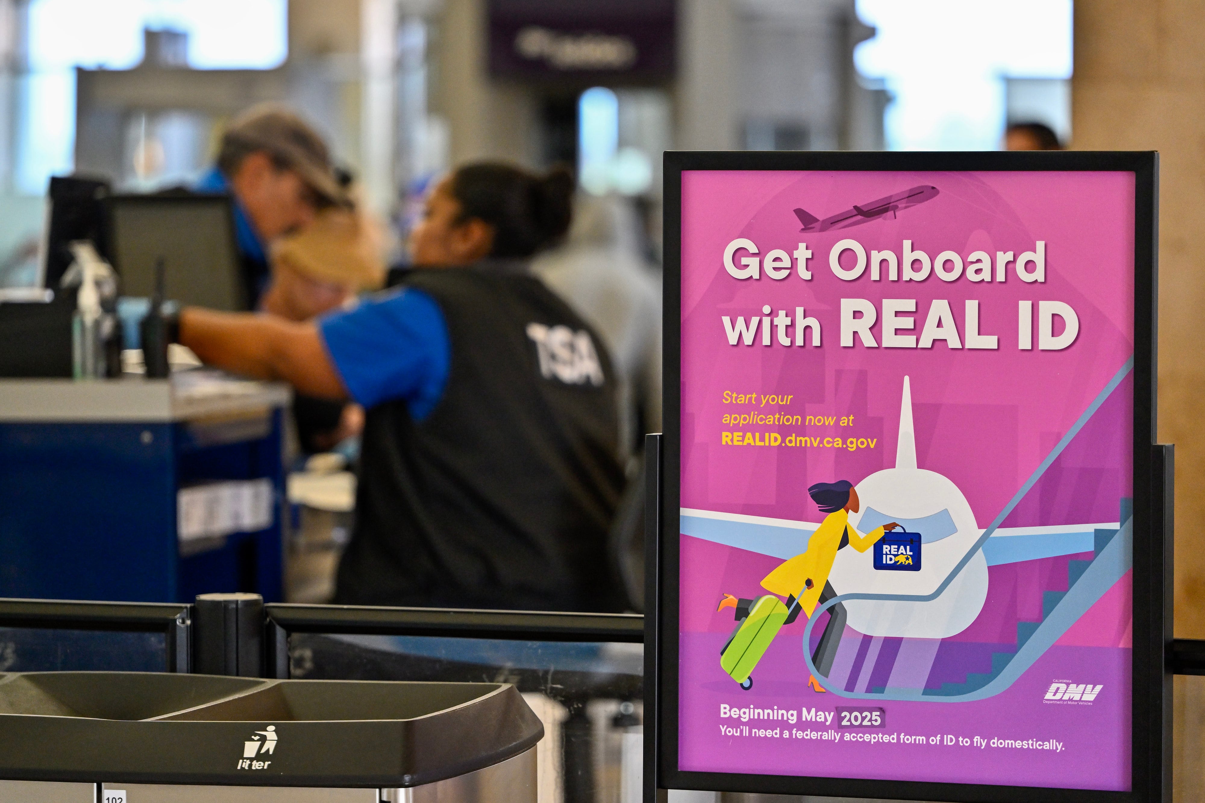 A pink sign rests behind TSA security personnel.