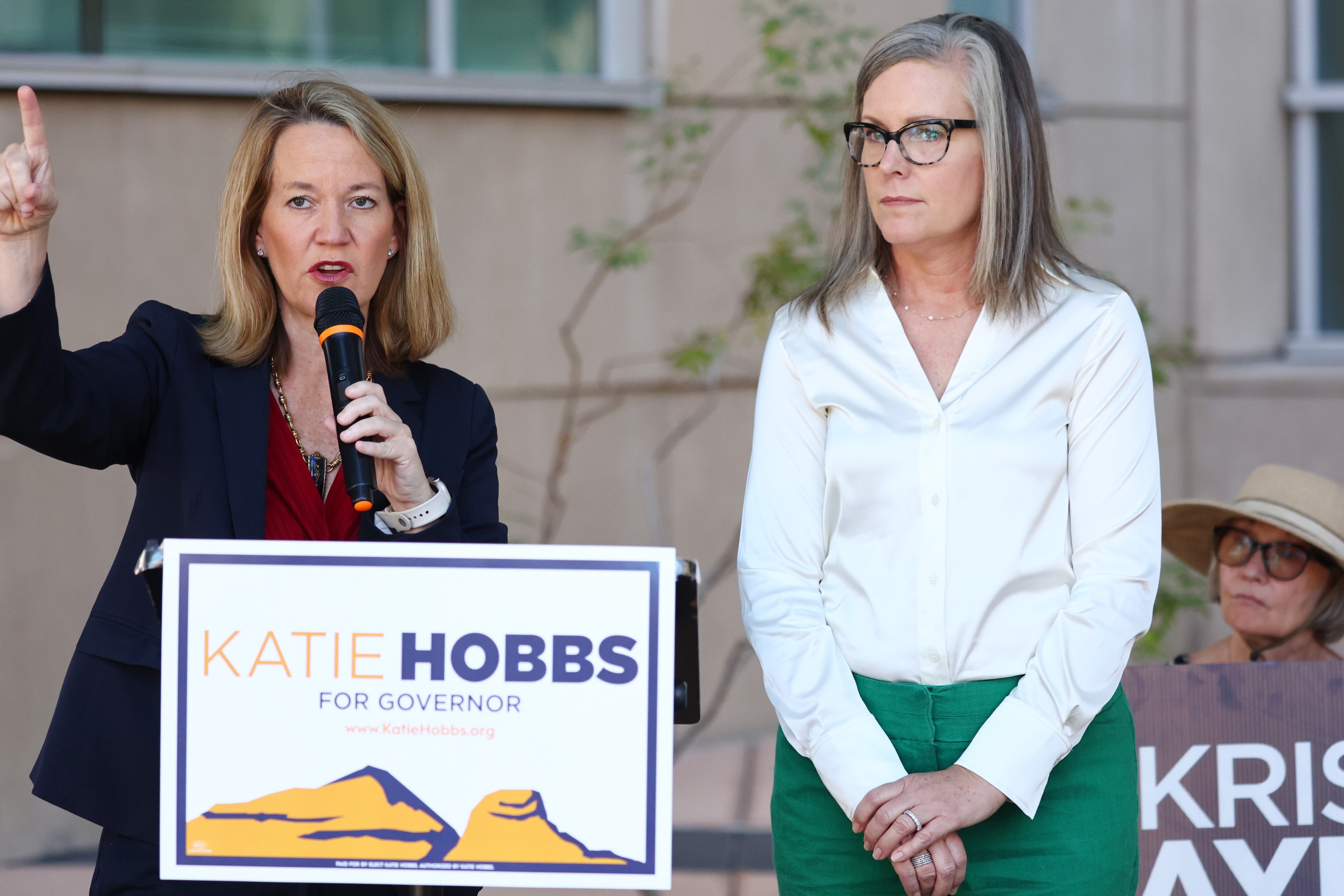 two women stand at podium