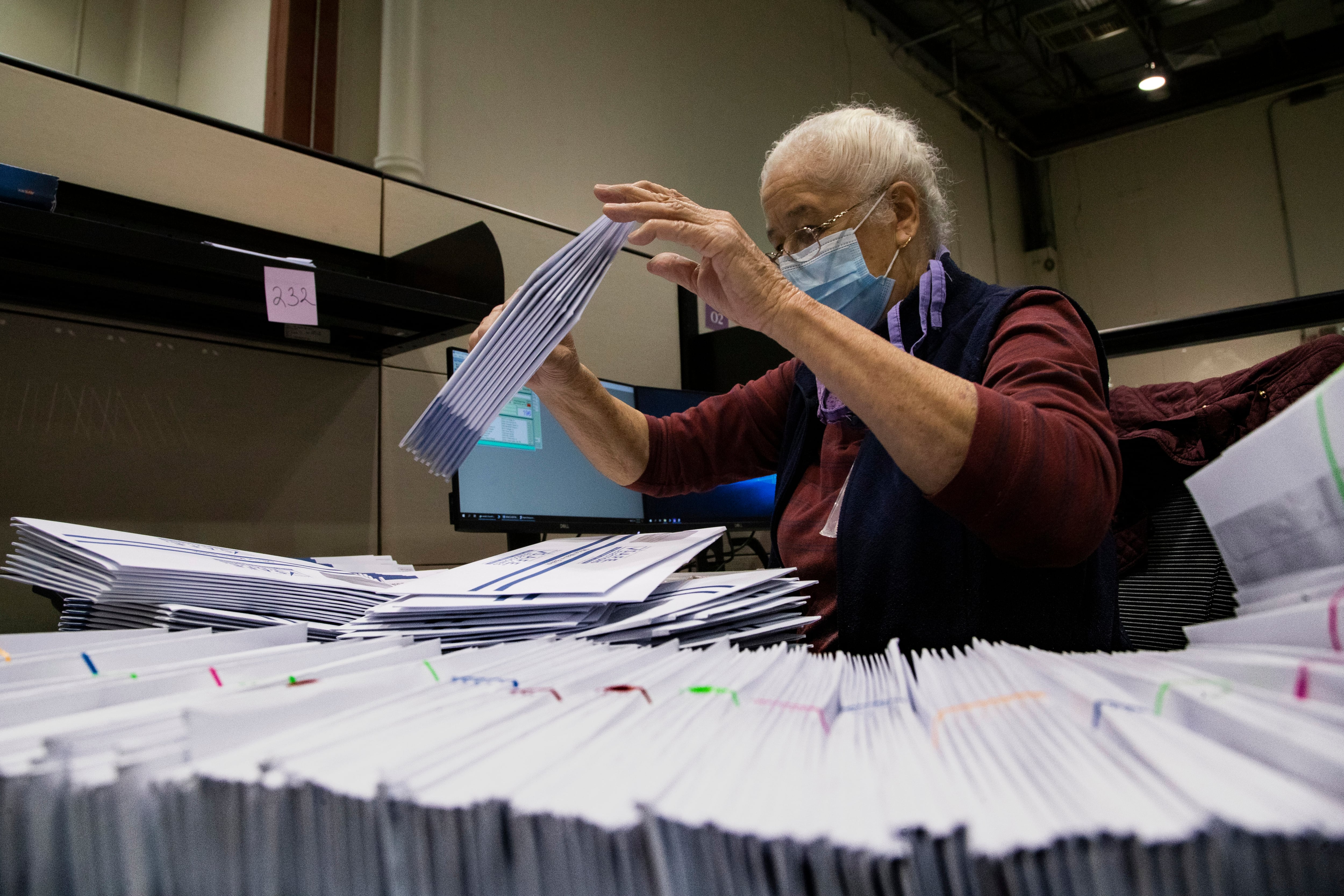 A man with a mask works with ballots.