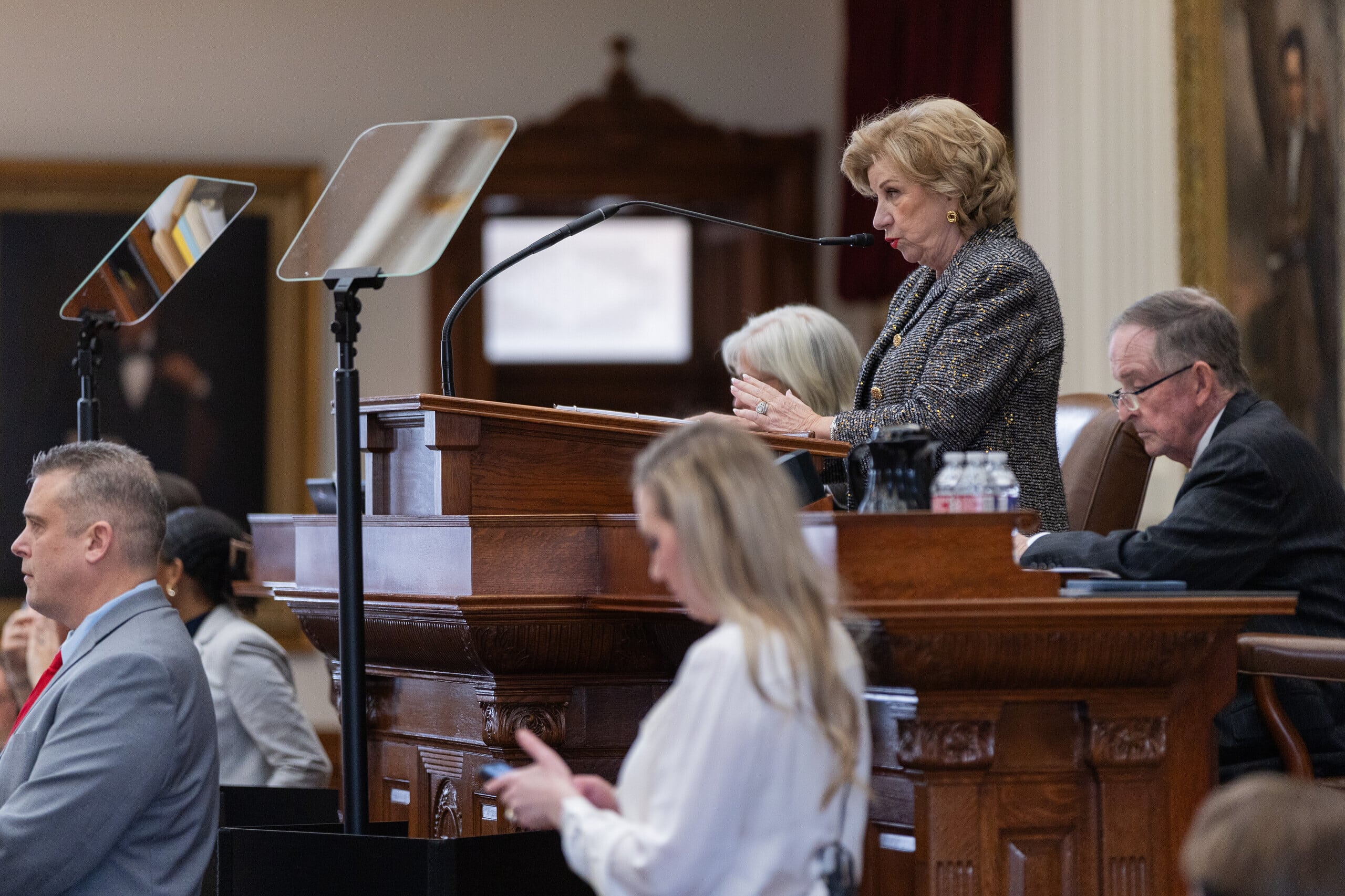 A white female is standing at a podium and speaking.