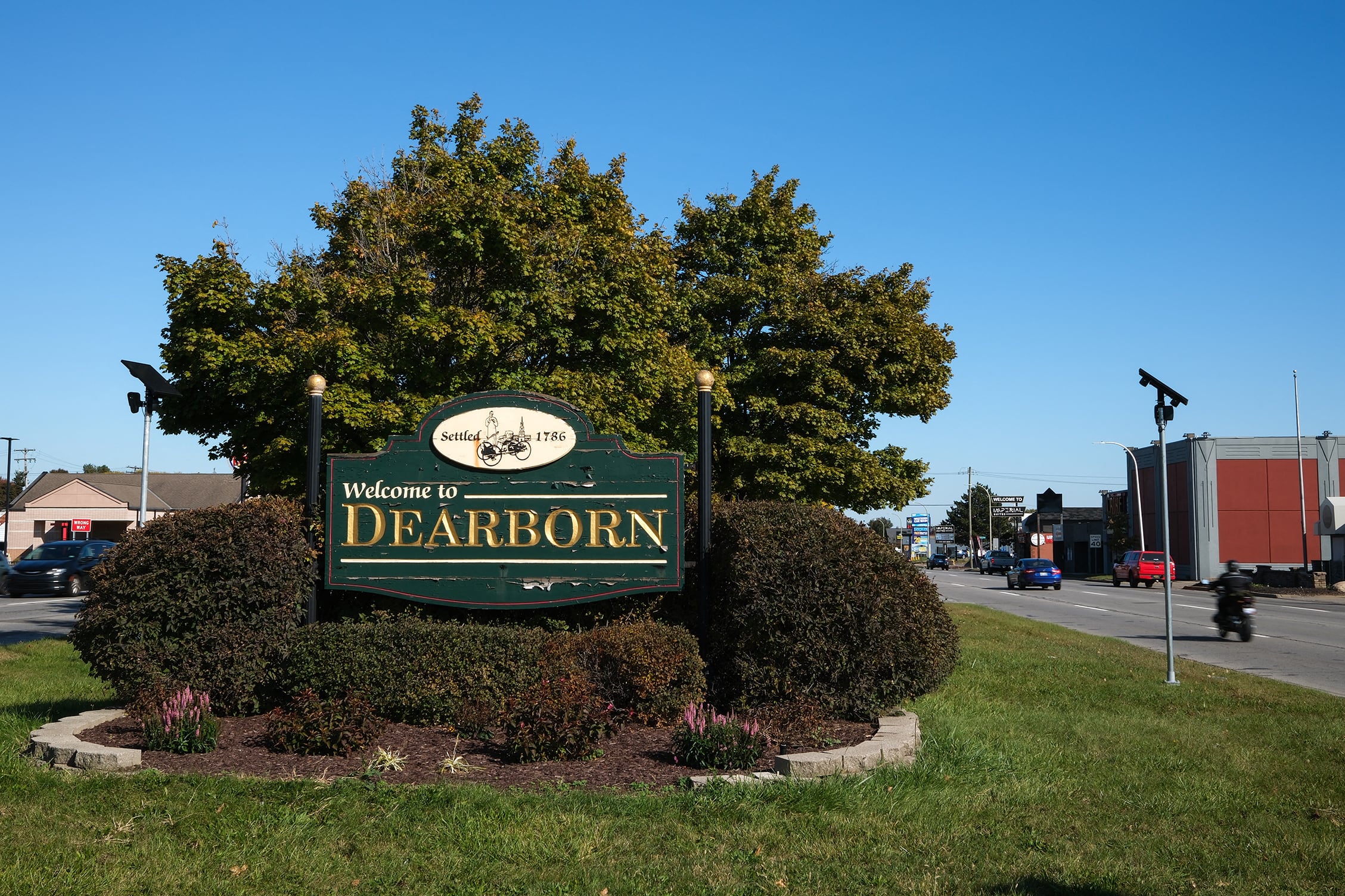 A photograph of a welcome sign by some trees outside.
