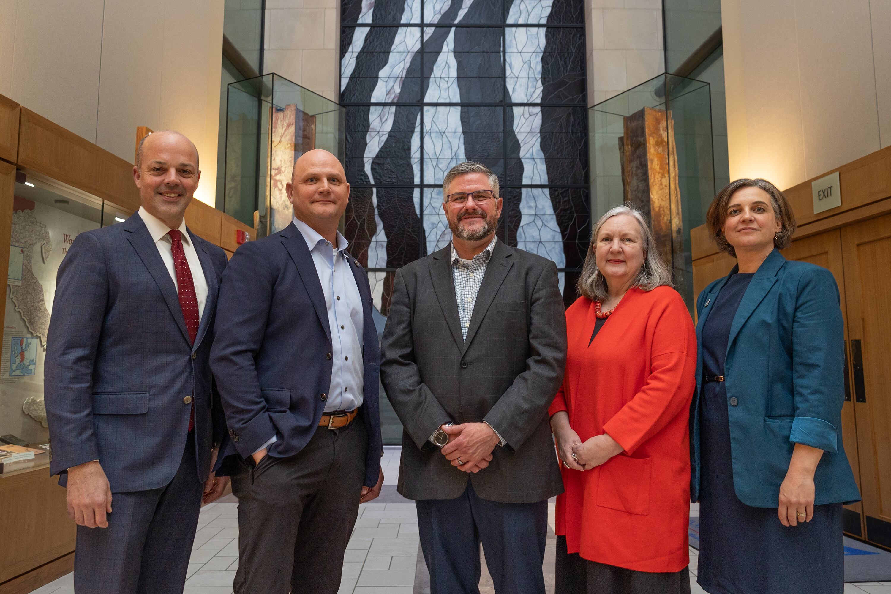 Five people in business clothing stands for a portrait inside.