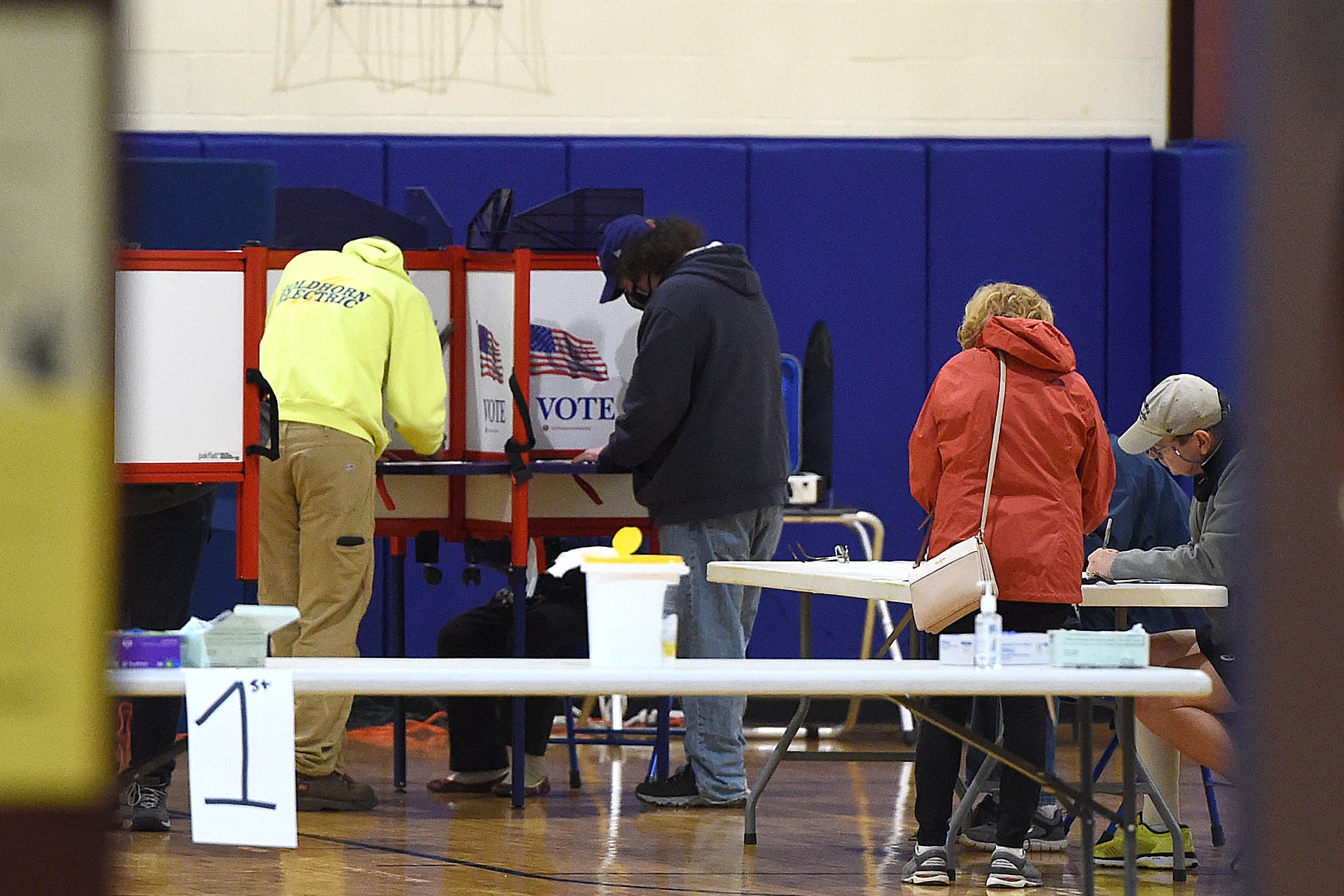 A photograph of a group of people voting in a school gym.