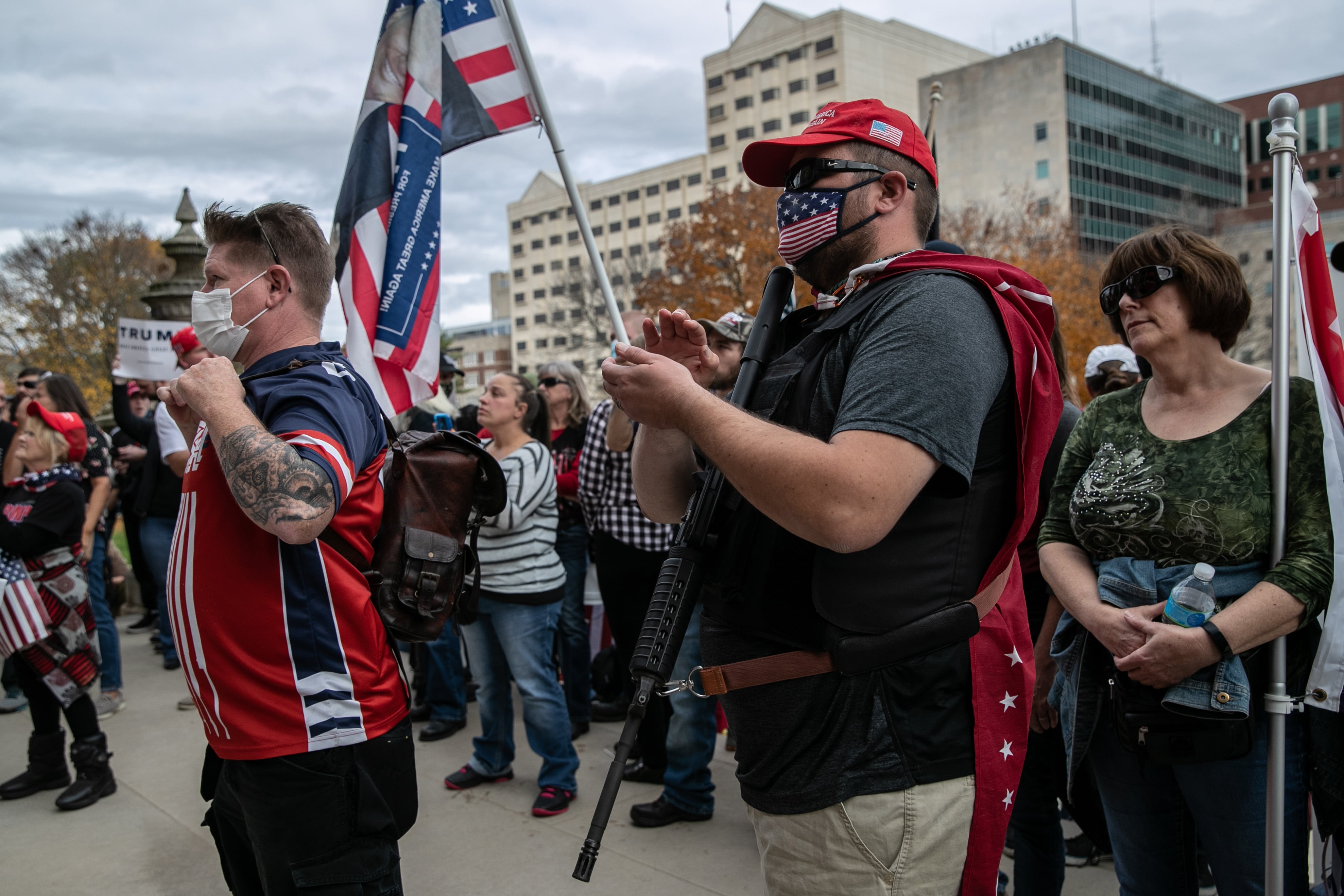 A man in a dark shirt and red cap holds a flag in a crowd of people.