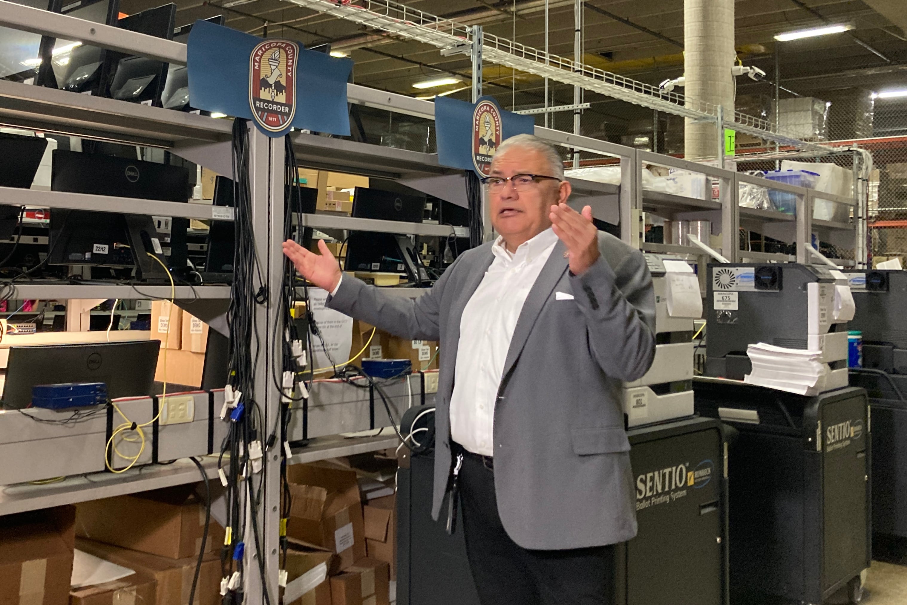 man in suit raises hands in warehouse