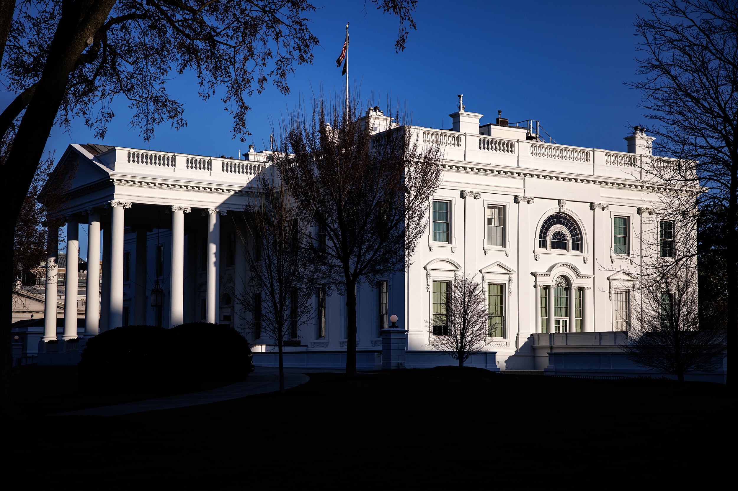 A large stone white building with some trees and a blue sky around it.